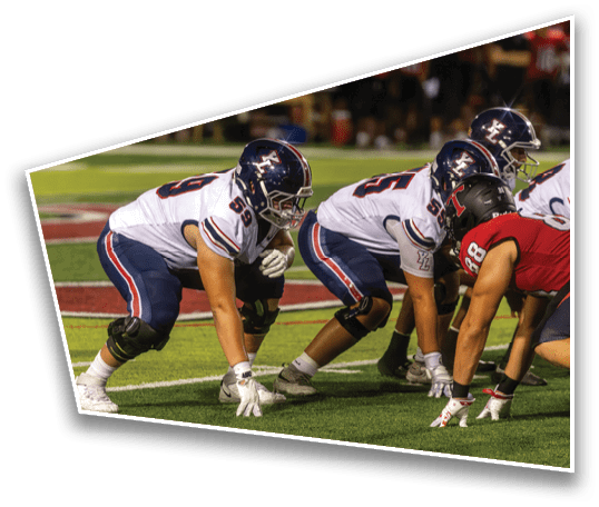 People wearing sports uniforms are gathered on the sidelines of a field with a crowd in the background. Description generated by AI