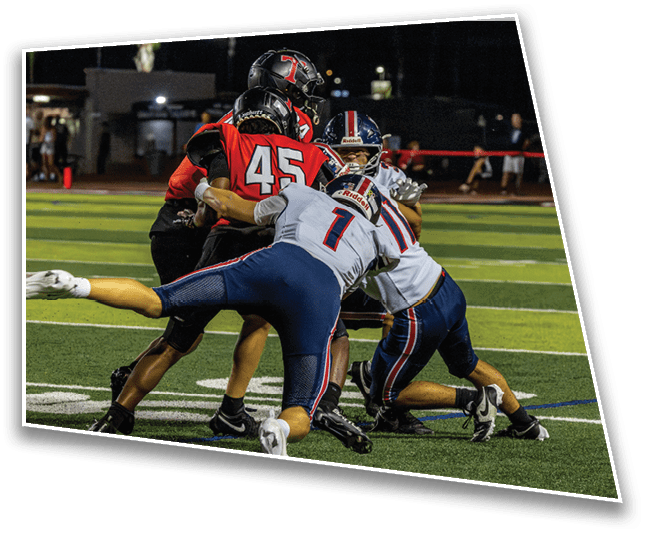 People in sports uniforms are crouched on a football field, preparing for a play. Description generated by AI