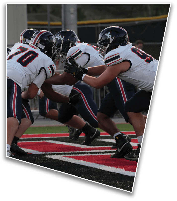 Two people in football uniforms are engaged in a play on a field with red and black markings. Description generated by AI
