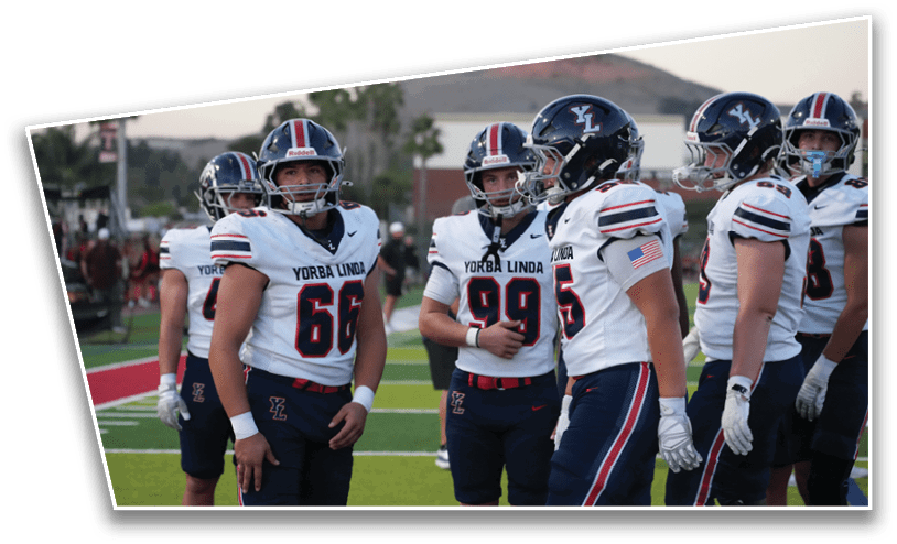 A group of people wearing football uniforms with helmets stand together on a field, appearing to be in conversation or preparing for a game. Description generated by AI