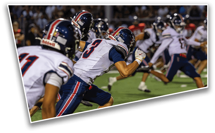 A group of people wearing helmets and sports uniforms are running on a field, appearing to be in the middle of a football game or practice. Description generated by AI