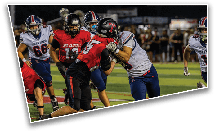 Two football players from opposing teams are engaged in a physical tackle on a field during a game. Description generated by AI