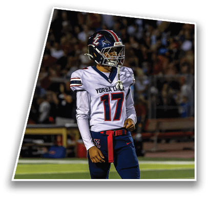A person wearing a Yorba Linda football uniform with the number 17 stands on a football field during a game. Description generated by AI