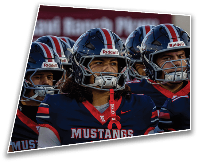 A group of people wearing dark blue football helmets with red and white stripes are closely gathered, appearing focused and ready for a game. Description generated by AI