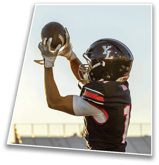 A person wearing a black sports jersey with the number one is preparing to throw a football in an outdoor stadium during sunset. Description generated by AI