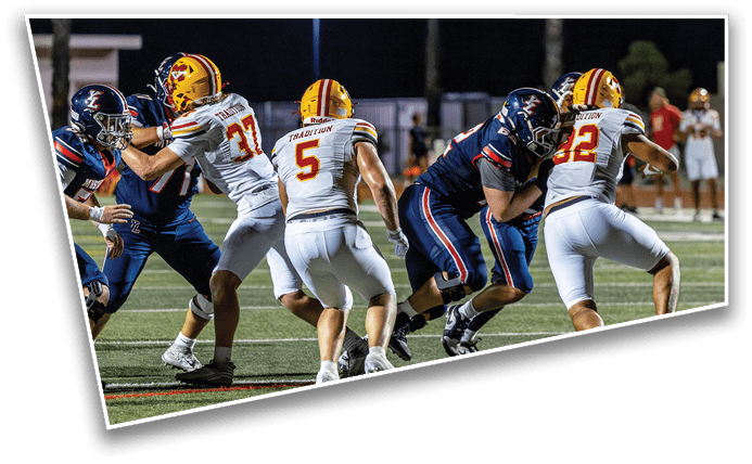 People wearing football helmets and uniforms are engaged in a game or practice on a field at night. Description generated by AI