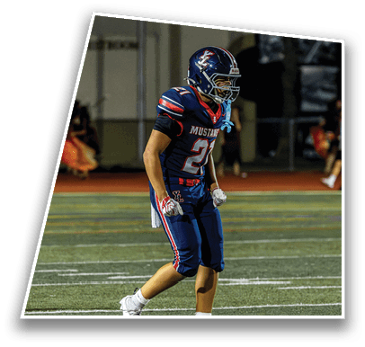 A person wearing a blue and red sports uniform with cleats is standing on a football field. Description generated by AI