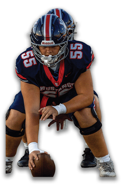 Two people in football uniforms and helmets are positioned closely with one holding a football ready to snap it. Description generated by AI