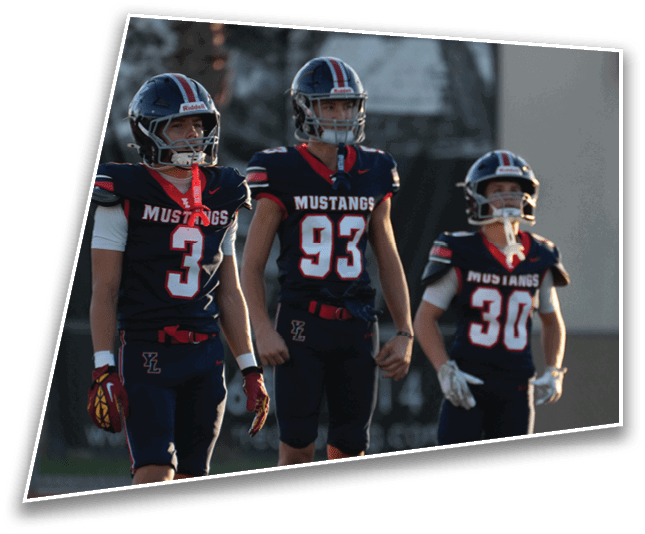 Three people in football uniforms and helmets stand on a field with a blurred background. Description generated by AI
