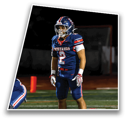 A person wearing a blue football uniform with the number 2 and the word Mustangs stands on a football field at night. Description generated by AI