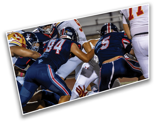 Several people in football uniforms are engaged in a close physical play on a field during a game. Description generated by AI