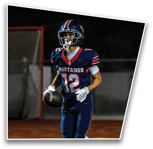 A person wearing a blue football uniform with the number 12 and the word Mustangs is running on a field while holding a football. Description generated by AI