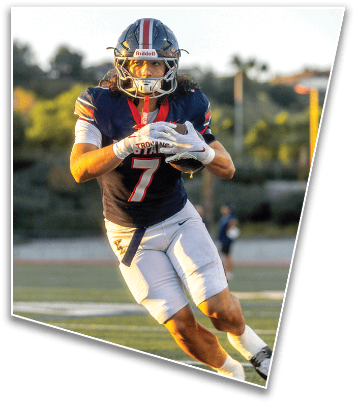A person wearing a football uniform with the number seven is running on a field while holding a football. Description generated by AI