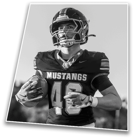 A person wearing a football uniform with the word Mustangs and the number 46 is holding a football and smiling outdoors. Description generated by AI