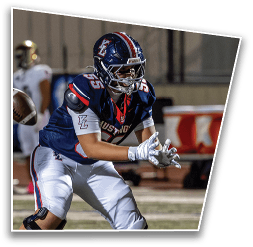 A person in a football uniform is preparing to catch a football on a field during a game. Description generated by AI