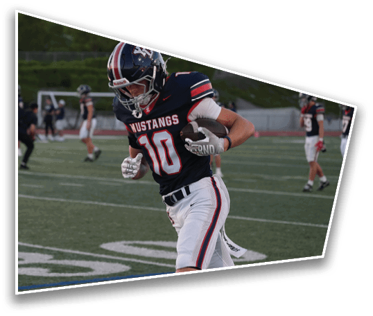 A person wearing a Mustangs football uniform with the number 10 is running on a football field during a game. Description generated by AI