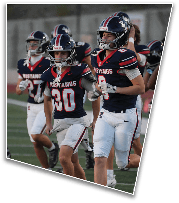Several people wearing football uniforms with helmets and “Mustangs" jerseys are running on a field during a game or practice. Description generated by AI