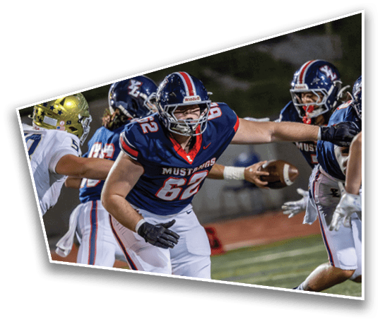 People in football uniforms are actively playing on a field with one person holding the ball and others reaching out during a game. Description generated by AI