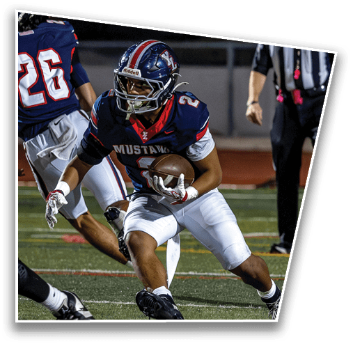 A person wearing a football uniform with the word Mustangs on the jersey is running on a field while holding a football. Description generated by AI