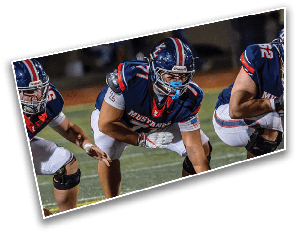 Three people in football uniforms and helmets are crouched in a ready position on a field during a game. Description generated by AI