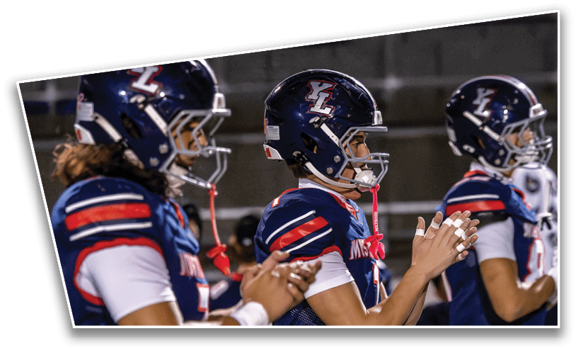 People wearing blue sports uniforms with red and white stripes are standing and clapping, likely at a sporting event. Description generated by AI