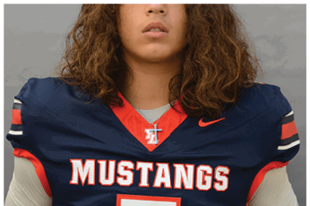 Person with long curly hair wearing a navy blue football jersey with “MUSTANGS" written on the front and a cross necklace. Description generated by AI