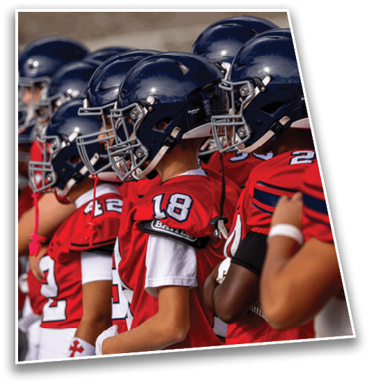 A group of people wearing red football jerseys and helmets stand closely together in a line. Description generated by AI
