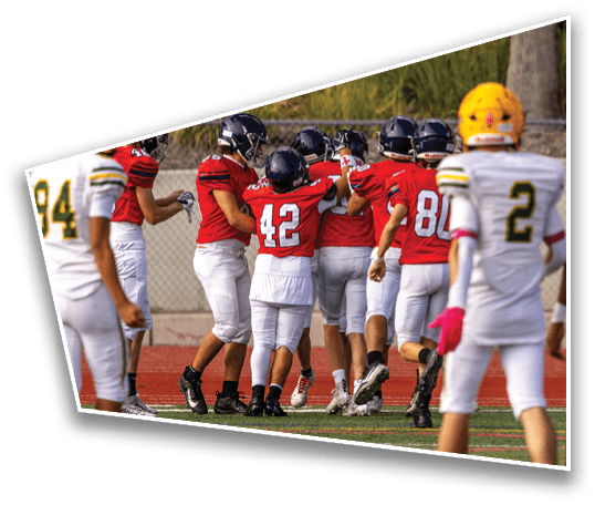 People wearing football uniforms in red and white are celebrating on a field while others in white and yellow uniforms stand nearby. Description generated by AI
