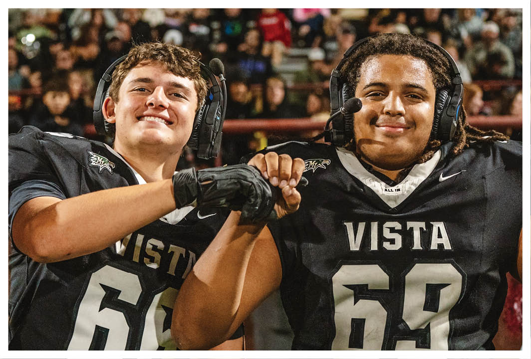 Two football players wearing black jerseys with the word Vista on them. Description generated by AI