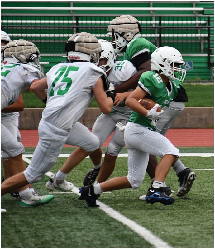Three football players in blue and white uniforms running on a field. Description generated by AI