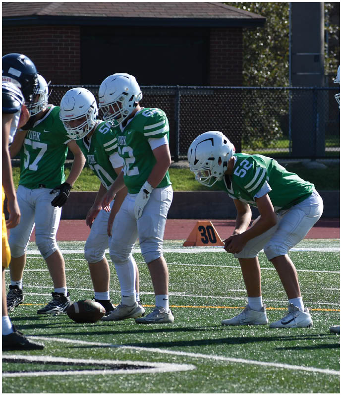 Three football players in blue and white uniforms running on a field. Description generated by AI