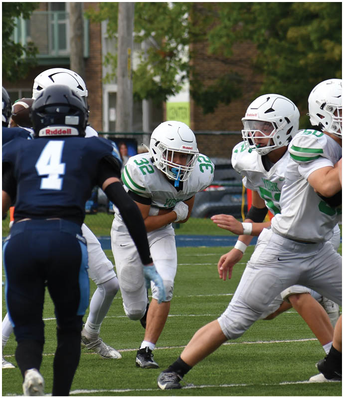 Three football players in blue and white uniforms running on a field. Description generated by AI