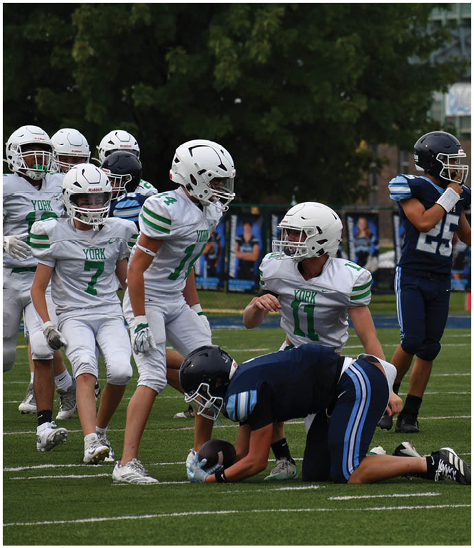 Three football players in blue and white uniforms running on a field. Description generated by AI