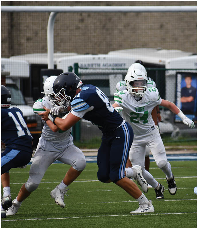 Three football players in blue and white uniforms running on a field. Description generated by AI
