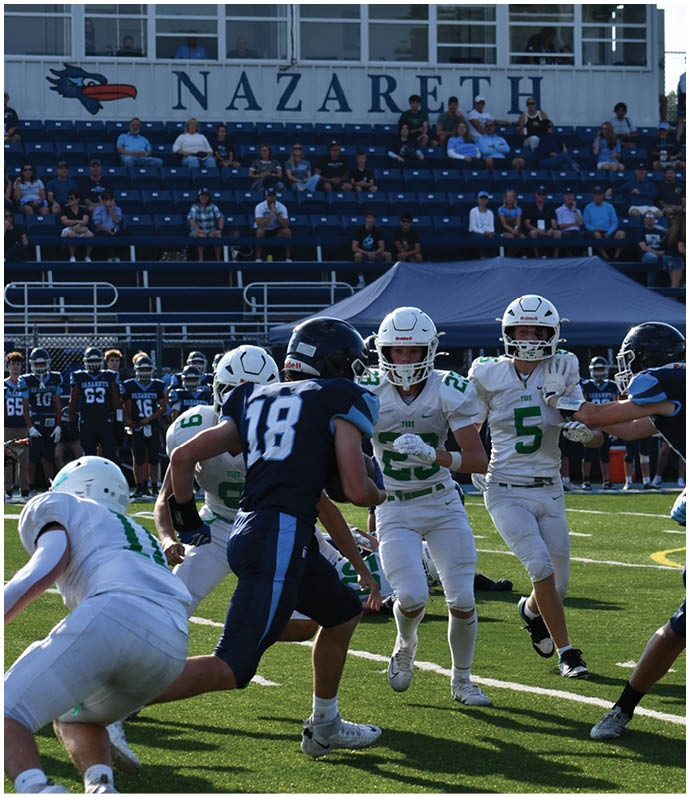 Three football players in blue and white uniforms running on a field. Description generated by AI
