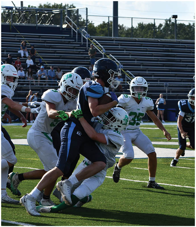 Three football players in blue and white uniforms running on a field. Description generated by AI