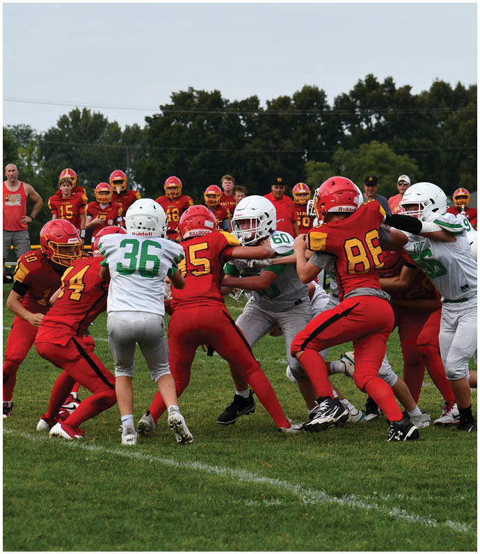 Three football players in blue and white uniforms running on a field. Description generated by AI