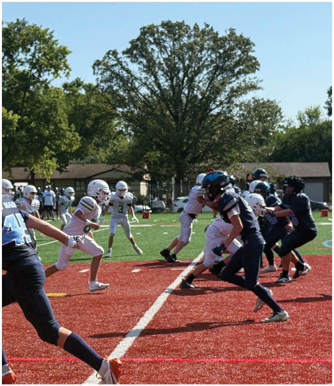Three football players in blue and white uniforms running on a field. Description generated by AI