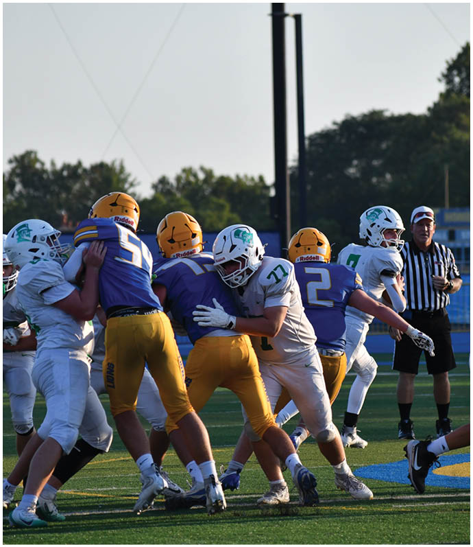 Three football players in blue and white uniforms running on a field. Description generated by AI