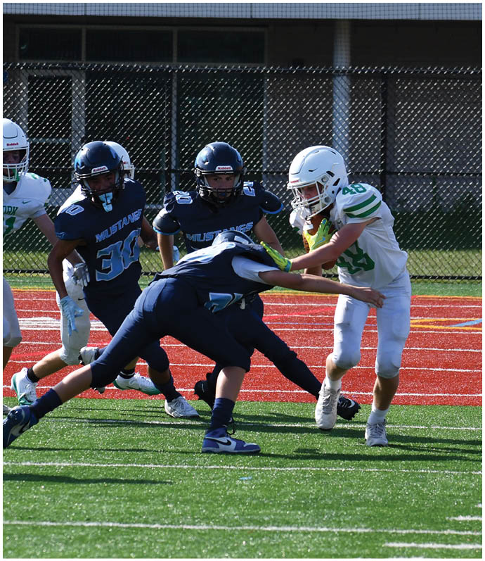 Three football players in blue and white uniforms running on a field. Description generated by AI
