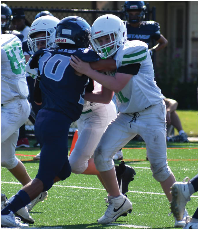 Three football players in blue and white uniforms running on a field. Description generated by AI