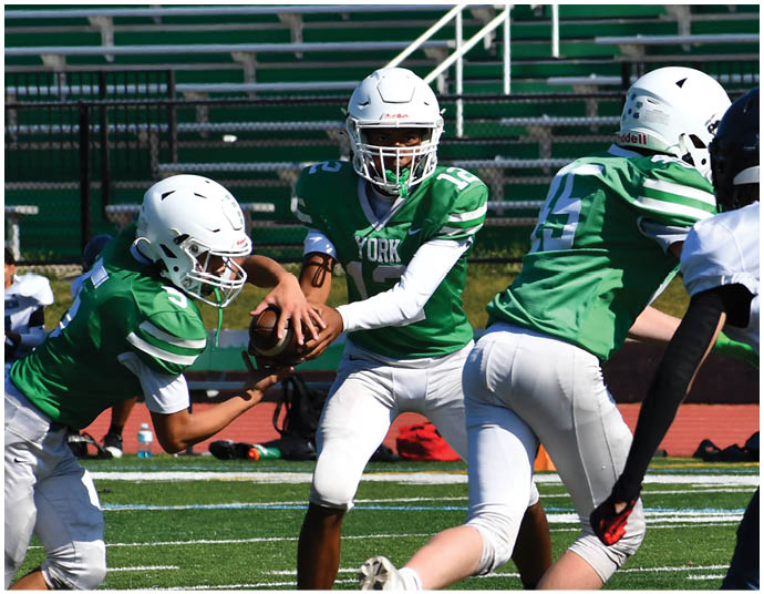 Three football players in blue and white uniforms running on a field. Description generated by AI
