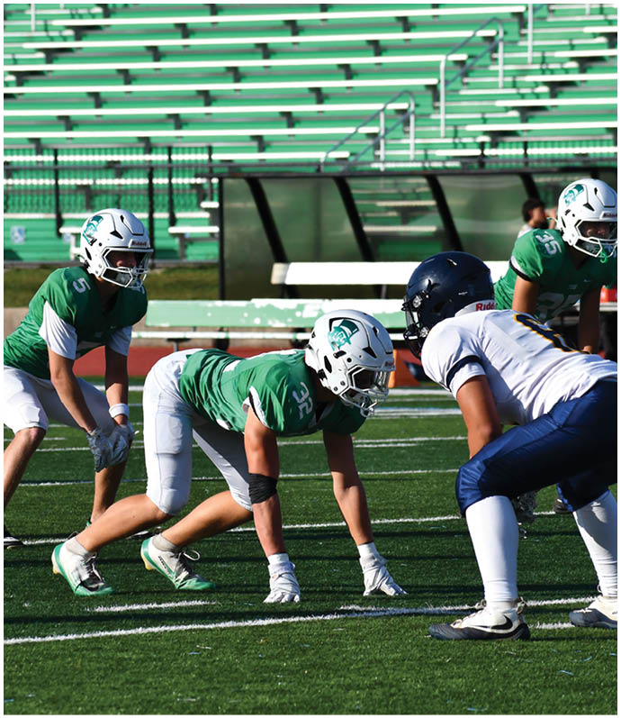 Three football players in blue and white uniforms running on a field. Description generated by AI