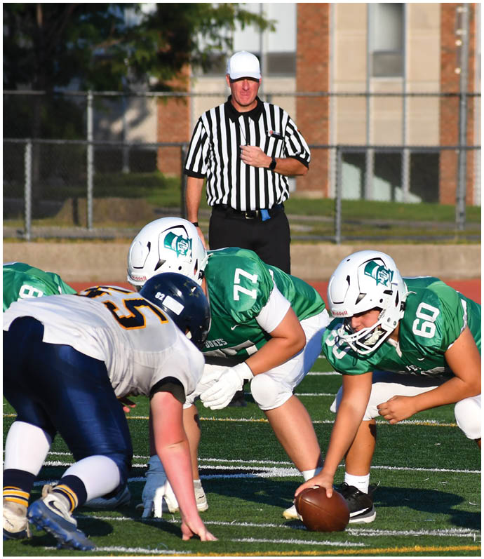 Three football players in blue and white uniforms running on a field. Description generated by AI
