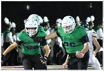 Two football players celebrating on the field. Description generated by AI