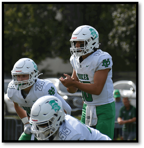 A football player wearing a black jersey with the number 6 on it. Description generated by AI