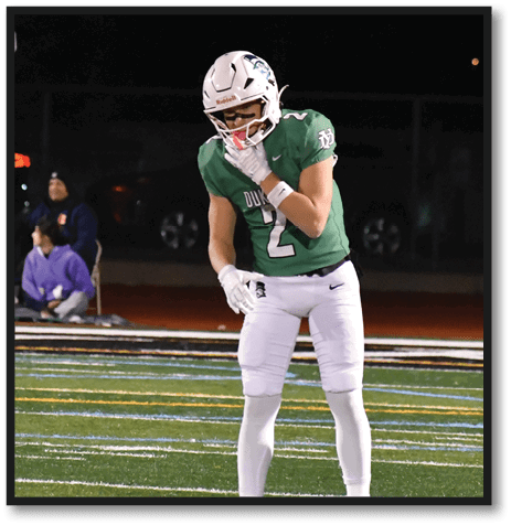 A football player wearing a black jersey with the number 6 on it. Description generated by AI