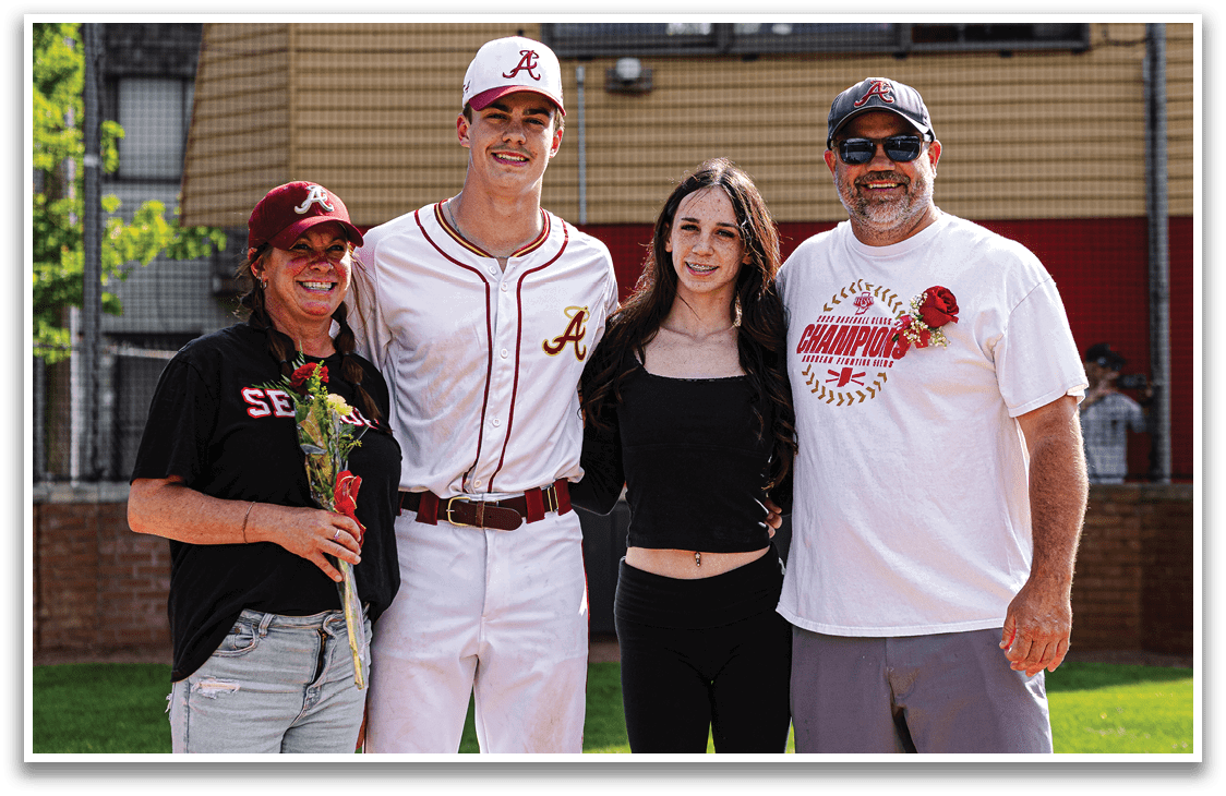 A man wearing a baseball uniform stands with a woman and two other people. Description generated by AI