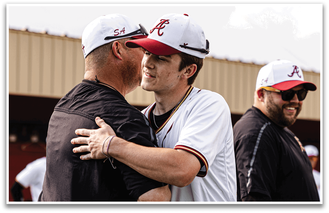 A man wearing a white baseball uniform is hugging another man. Description generated by AI
