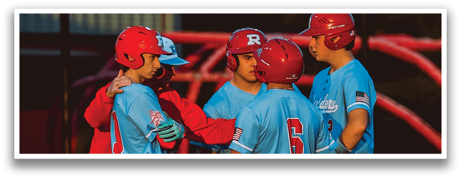 A group of people wearing red and blue shirts are standing on a baseball field. Description generated by AI